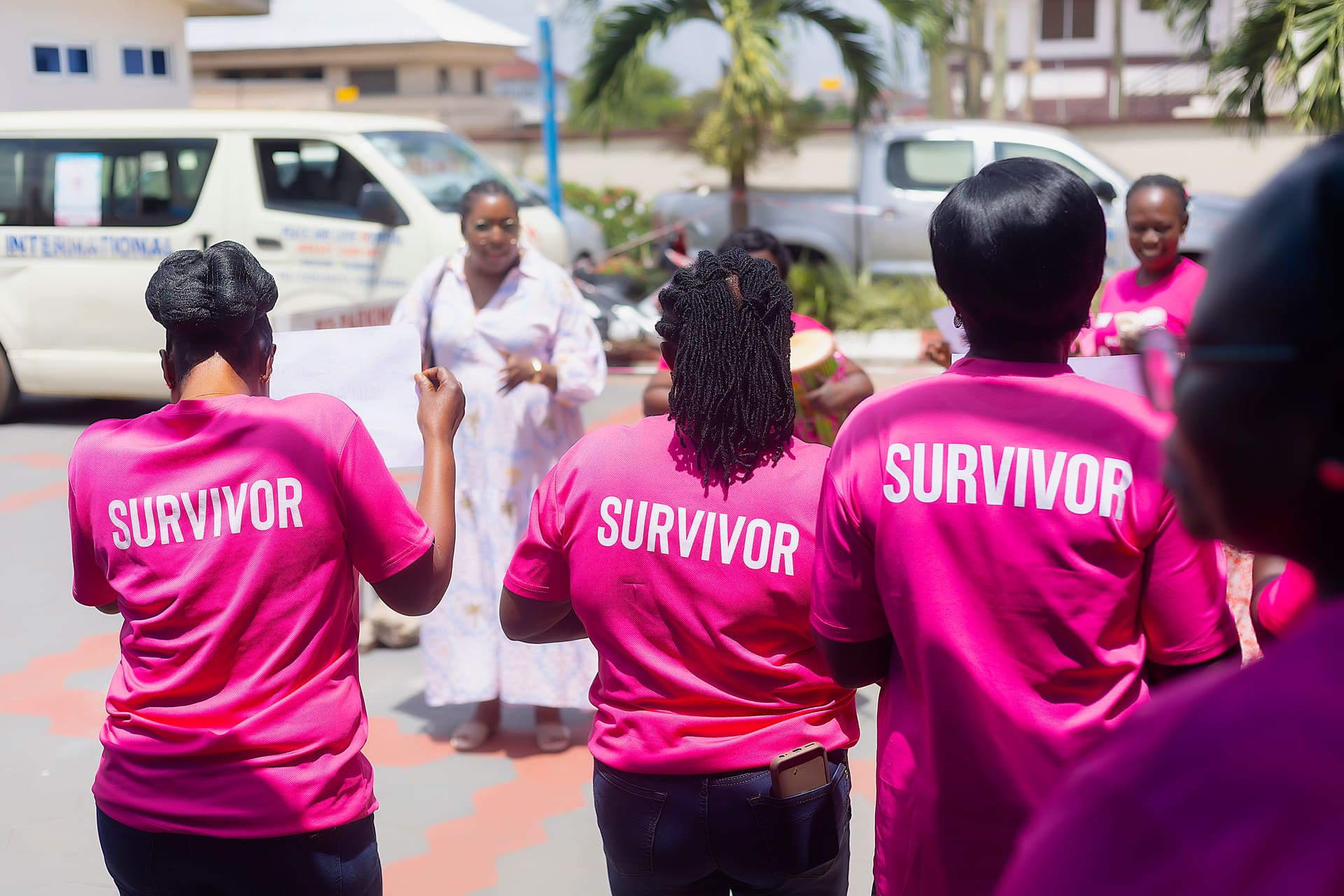 PALSA members in pink SURVIVOR shirts gathered around a speaker at a survivors' meeting